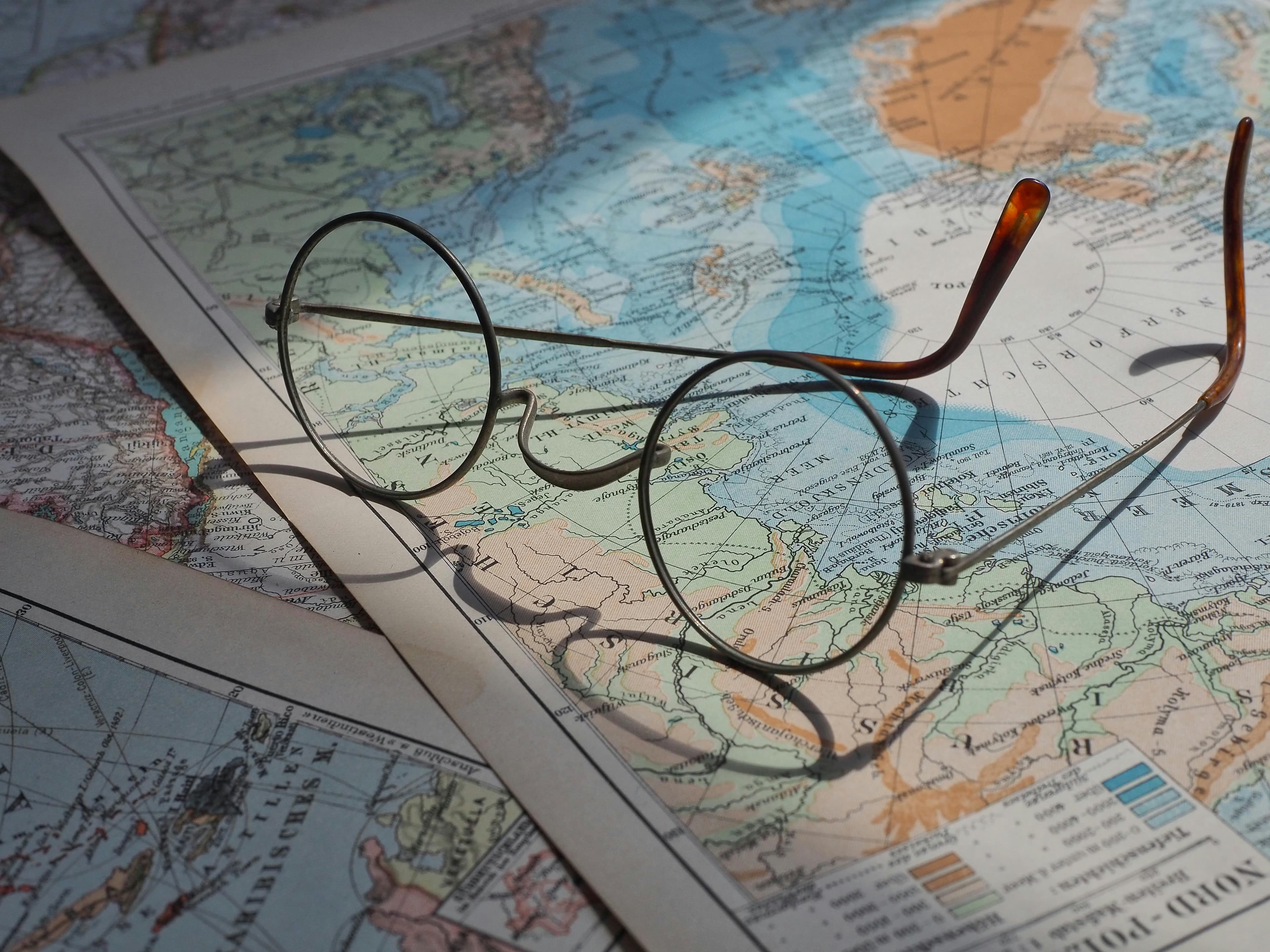 Round-rim glasses resting on a vintage world map — an artifact of curiosity.